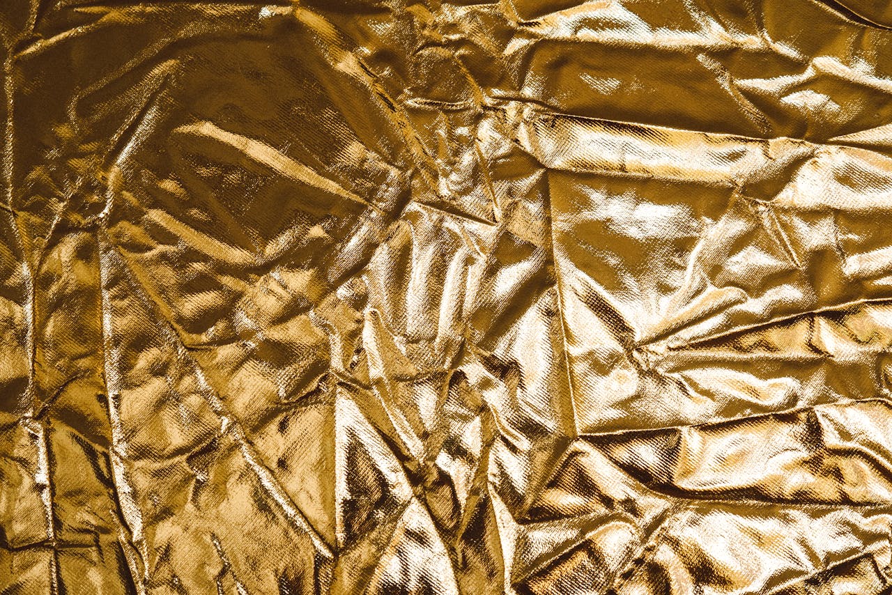 High-resolution image of crumpled gold fabric, perfect for backgrounds and designs.